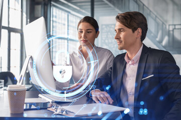 Businessman and businesswoman working together to protect clients confidential information and cyber security. IT hologram padlock icons over office background with panoramic windows.