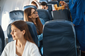 Thankful passenger passing her carry-on package to flight attendant