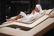 © Viacheslav Yakobchuk - Beautiful charming Caucasian woman with towel on head sitting on deck chair in spa resort hotel
