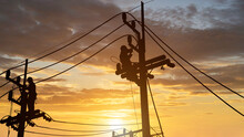 Silhouette Electricians Work On High Voltage Towers To Install New Wires And Equipment.