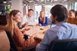 © Monkey Business - Business Team Having Meeting Sitting Around Table In Modern Open Plan Office
