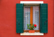 blossoming red hibiscus at a window on a red wall, Burano, Venice