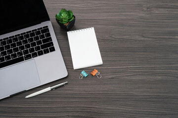 Wall Mural - Work space, office business and education concept on modern table desk with blank notepad for put your text and laptop computer, green plant, Top view with copy space