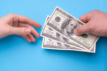 Male Hand Gives 300 Dollars To Female Hand, Blue Background