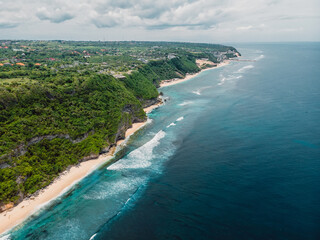 Aerial view of coastline with tropical beach, cliff and ocean and waves in Bali, Bukit