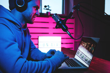 Wall Mural - Streamer  broadcasting his live audio show at home studio using stylish cyber punk blue magenta ambient light