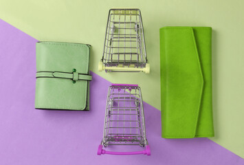 Two mini supermarket trolleys with wallet on colored background