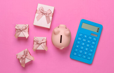 Wall Mural - Piggy bank and gift boxes, calculator on pink background. Minimalistic studio shot. Overhead view. Flat lay.