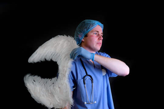 A doctor in a blue uniform puts on white angel wings on a dark background
