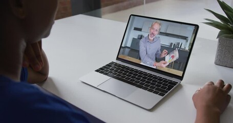 Wall Mural - African american businesswoman sitting at desk using laptop having video call with male colleague