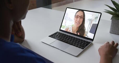 Wall Mural - African american businesswoman sitting at desk using laptop having video call with female colleague