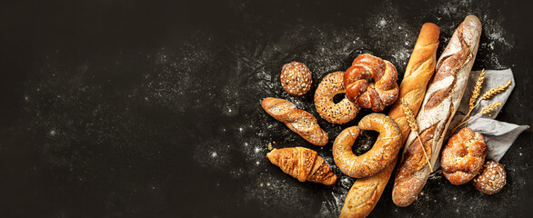 Bakery - bread rolls, baguette, bagel, sweet bun and croissant on black background