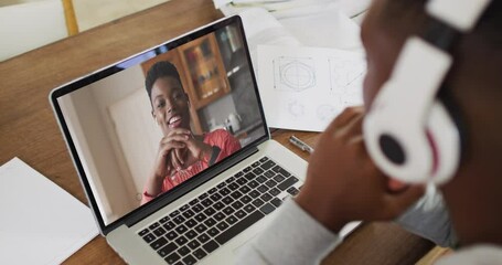 Canvas Print - African american male college student holding notes while having a video call on laptop at home