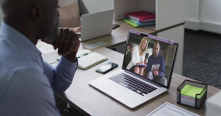 Poster - African american senior man having a video call with male and female colleagues on laptop at office