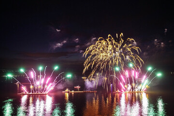 Wall Mural - Holiday fireworks above water with reflection on the black sky background