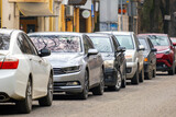 Fototapeta Kwiaty - Cars parked in a row on a city street side.
