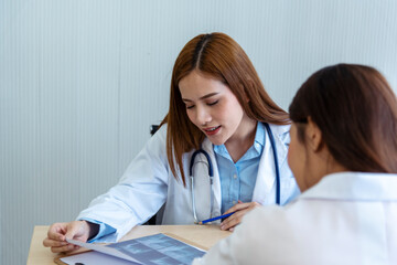 Two asian women doctors discuss meeting doctor's office medical clinic looking x-ray film consulting patient disease. Asian medical lab young women talking together discussing healthcare teamwork