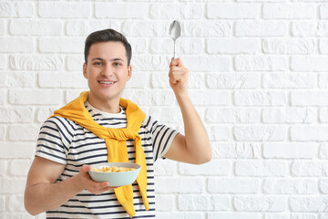 Poster - Young man and bowl with cornflakes on brick background