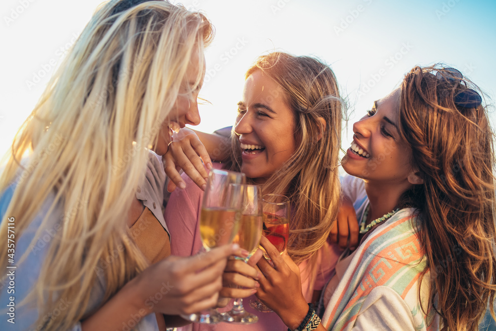 Happy young women drinking champagne at bachelorette party on the beach - obrazy, fototapety, plakaty 