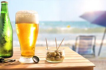 Beach bar concept with wooden table with beer and olives