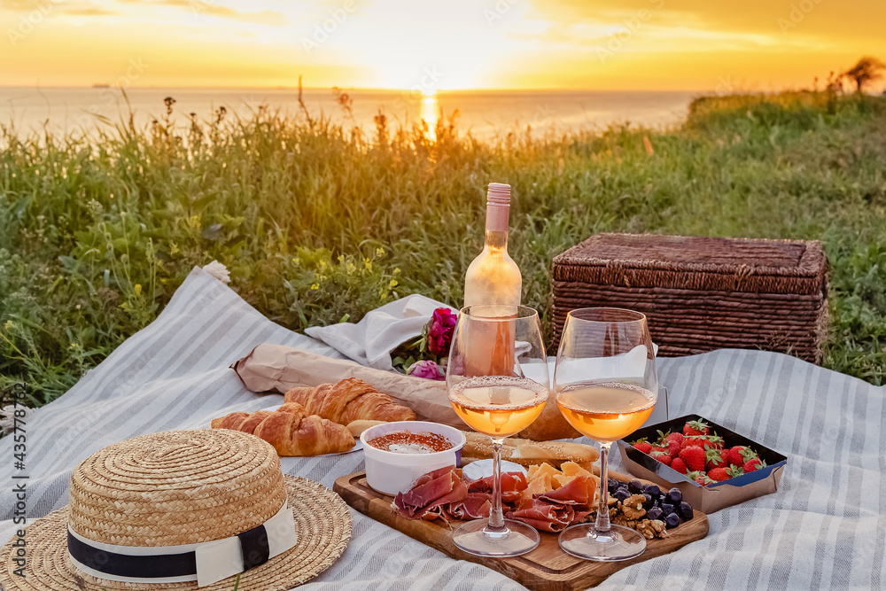 Picnic with strawberries, croissants and appetizers on the board and rose wine. - obrazy, fototapety, plakaty 