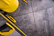 Contractor theme. Tool kit of the contractor: yellow hardhat, libella and tools on the gray tiles background.