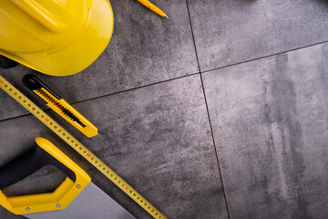 Sticker - Contractor theme. Tool kit of the contractor: yellow hardhat, libella and tools on the gray tiles background.