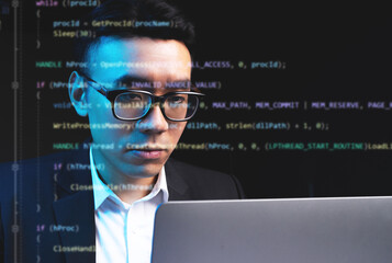 asian man focusing on programming with lines of code running on the screen