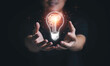 © Dilok - Man hand holding hanging glowing drawing light bulb with orange rays , creative thinking idea and innovation concept.