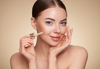 Wall Mural - portrait beautiful young woman with clean fresh skin. model with foundation makeup bottle. cosmetolo