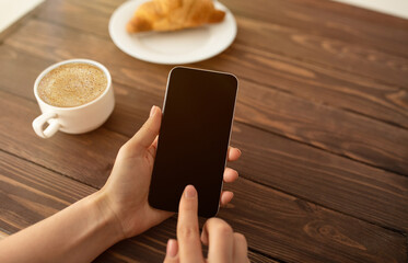 Poster - Cool app. Woman using smartphone with black screen and drinking coffee at cafe, closeup