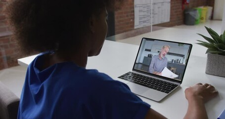 Sticker - Back view of african american woman having a video call on laptop with male colleague at office