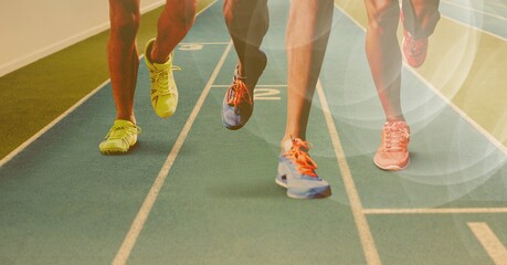 Canvas Print - Composition of legs of running athletes on racing track with spots of light