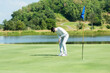 © freebird7977 - Golfer man playing golf aiming shot for putting ball on the hole with club on green course.  Professional people hobby in holiday and vacations in sunny morning day on club golf