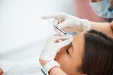 Wall Mural - Woman getting a dermal filler injection into the glabellar line