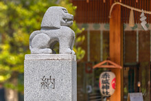 Japanese Komainu Lion Statue Designed By Architect Kengo Kuma In The Akagi Shrine Of Kagurazaka Adorned With The Carved Word Dedication And A Paper Lantern In Background.