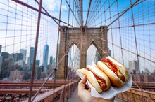 Holding Two Hot Dogs In NYC On The Brooklyn Bridge