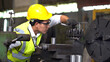 © iammotos - asian worker wearing helmet and safety glasses working  with machine in factory . industrial engineer operating lathe machine
