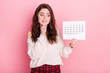 Sticker - Photo of guilty unsure young woman dressed white sweater biting lip holding calendar empty space isolated pink color background