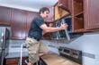 © spatesphoto - Appliance technician installing a microwave