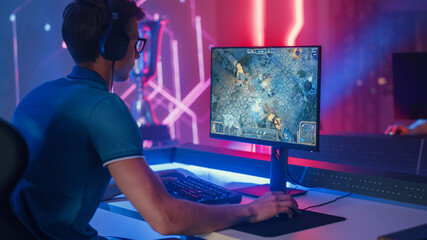 Wall Mural - Professional eSports Gamer Plays RPG MOBA Mock-up Video Game with Super Action and Fun Special Effects on His Personal Computer, Talks to Teammates using Headset. Cyber Gaming Stylish Retro Neon Room