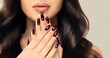 Beautiful girl showing red burgundy  manicure nails . makeup and cosmetics. Brunette  woman with long  and   shiny curly hair