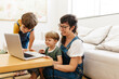 © (JLco) Julia Amaral - Cute young family looking at a laptop together while at home