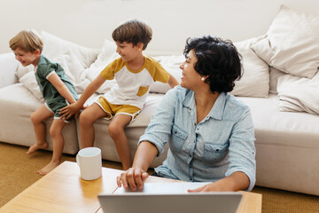 Wall Mural - Kid playing at home with mom working on laptop