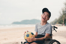 Asian Special Child On Wheelchair On The Beach With Parents In Family Holiday To Travel, Exercise And Learning About Nature Around The Sea Beach, Life In The Education Age, Happy Disabled Kid Concept.