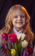 © Екатерина Клищевник - little girl with flowers tulips on a dark background