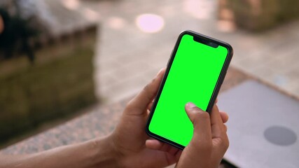 close up male hands holding smartphone with green touchscreen african guy typing or scrolling or shopping online outdoors