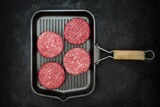 Fototapeta Desenie - Raw Minced Homemade Grill Beef Burgers in Frying Pan, Top View. Griddle Grill Pap and Ground Beef Meat Patties for Grilling on Black Background, Overhead View. Raw Steak Burgers Cutlets On Grill Pan.