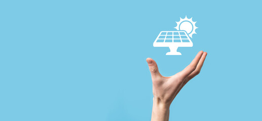 Wall Mural - Hand on a blue background holds the icon symbol of solar panels. Renewable energy, solar panels station concept, green electricity