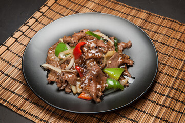 Beef in black bean sauce with red and green peppers at a Korean restaurant.